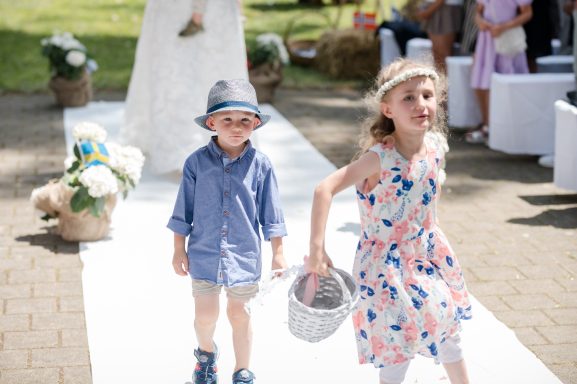 Ein Junge in blauer Kleidung und ein Mädchen in einem bunten Kleid gehen auf einem Laufsteg.